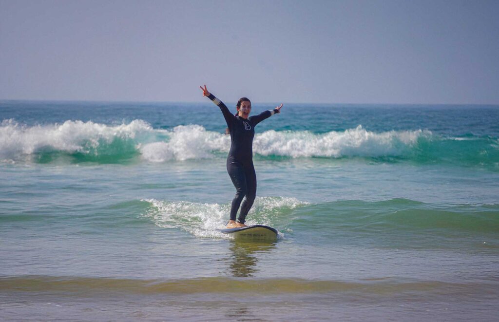 Happy female surfer riding a small wave in Tamraght, Morocco during a surf retreat