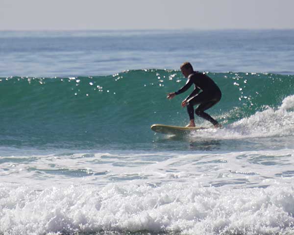 Intermediate surfer riding a clean mid-size wave in Taghazout, Morocco