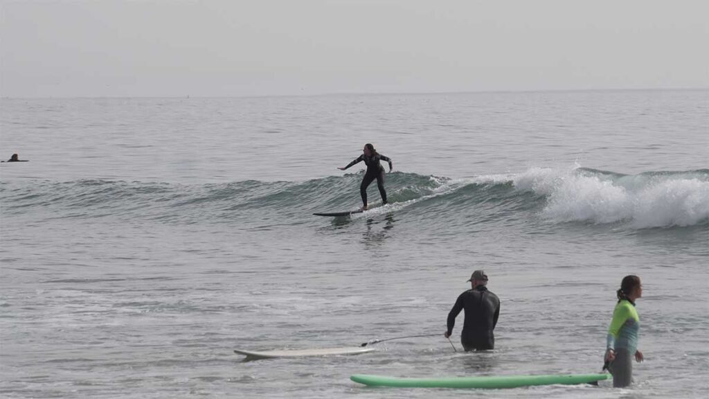 Beginner surfer riding green wave during lesson near Tamraght