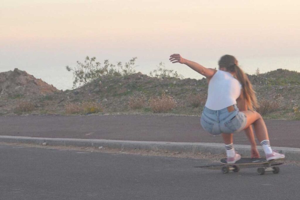 What to wear in Morocco as a Woman: A Practical Guide for Tamraght and surf towns 4 Woman surfskating at sunset in jean shorts and a white T-shirt in Tamraght
