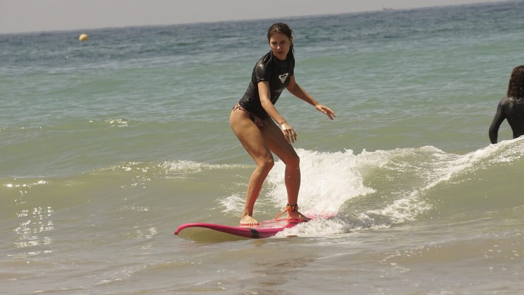 Morocco Surf Conditions explained for Beginners: Swell, Wind, Tides and Wave Size 3 Beginner woman surfer surfing a small wave next to Tamraght